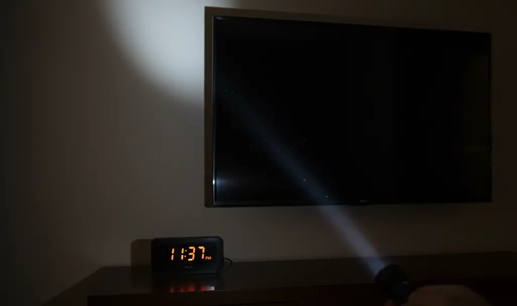 Image showing Searching for a hidden camera in a hotel room with a smartphone flashlight.